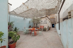 A courtyard with a covered seating area, potted plants, and a wall with a message. - Clerigos Loft by Hosty (Oporto)