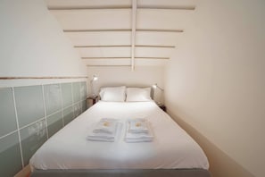 A narrow hotel room with a bed, two bedside tables with lamps, and a tiled wall. - Clerigos Loft by Hosty (Oporto)