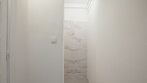 A narrow hallway with white walls and a marble-patterned shower area. - Clerigos Loft by Hosty (Oporto)