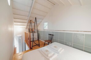 A bedroom with a bed, a chair, a wooden ladder, and a small window. - Clerigos Loft by Hosty (Oporto)
