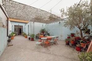 A covered patio with a table and chairs, surrounded by potted plants. - Clerigos Loft by Hosty (Oporto)