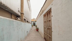 A narrow alleyway with a corrugated metal wall on the left and a wooden door on the right. There are potted plants along the alley. - Clerigos Loft by Hosty (Oporto)