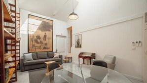A modern living room with a glass table, grey sofa, and wooden shelving. - Clerigos Loft by Hosty (Oporto)