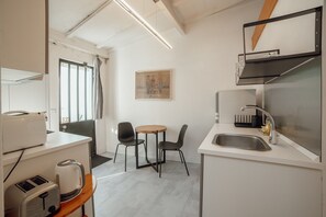 A modern kitchen with a dining area, featuring a sink, countertop, and chairs. - Clerigos Loft by Hosty (Oporto)