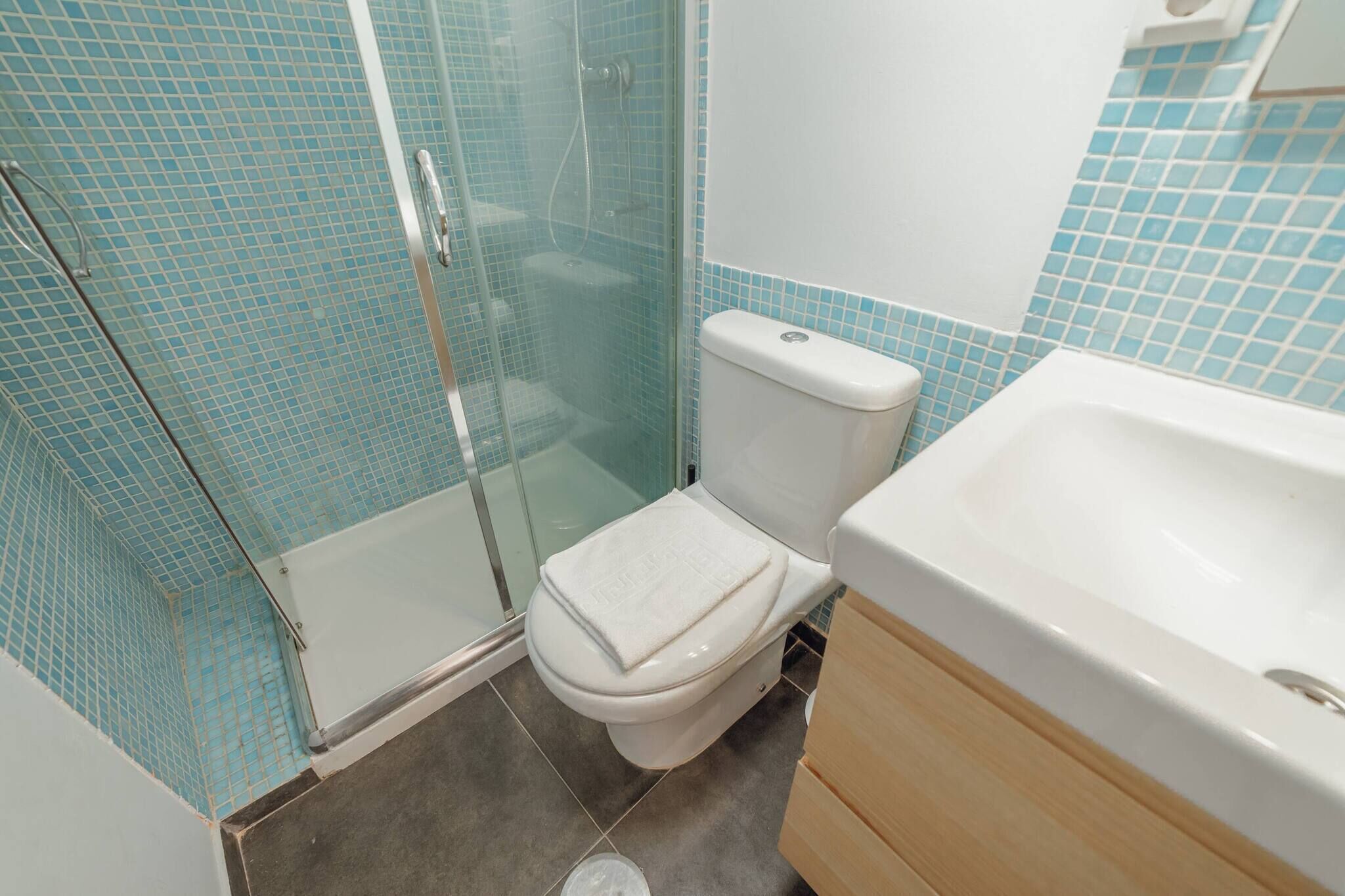 Une salle de bain avec une douche à parois en verre, des toilettes et un lavabo.