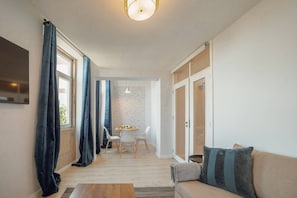 En moderne stue med sofa, sofabord og et spiseområde med stole og bord.
