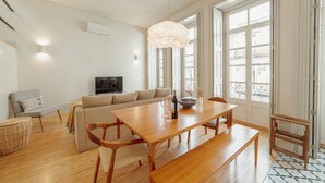 Ein modernes Wohnzimmer mit Esstisch aus Holz, einer Couch und einem Fernseher.