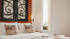 A neatly made bed with white linens and two decorative pillows, a wooden headboard with a metal design, and a window with daylight coming through. - Downtown Bolhão 3 by Hosty (Porto)