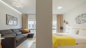 Un salon moderne avec un canapé gris, un coussin jaune et une table basse blanche.
