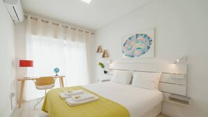Une chambre d’hôtel comprenant un lit, un bureau, une chaise, une lampe et une œuvre d’art murale.