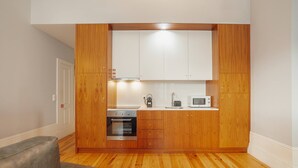 Una cocina compacta con armarios de madera, horno empotrado, microondas y cafetera.