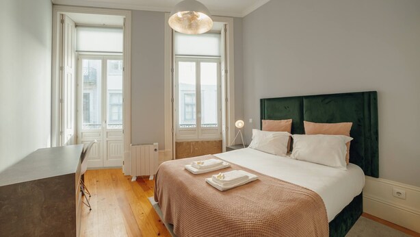 Un dormitorio con cama, mesitas de noche, escritorio y ventana.