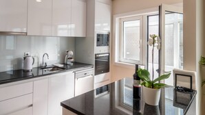 Een moderne keuken met witte kasten, roestvrijstalen apparatuur, een zwart aanrecht en een raam met uitzicht op de stad.