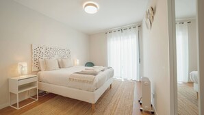 Een moderne slaapkamer met een groot bed, nachtkastje en een bijzettafeltje.