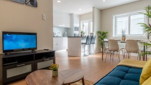 Een moderne woonkamer met een televisie, bank en eethoek.