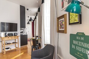 Ein modernes Wohnzimmer mit Fernseher, Holzmöbeln, einem Essbereich und einem grünen Schild an der Wand.
