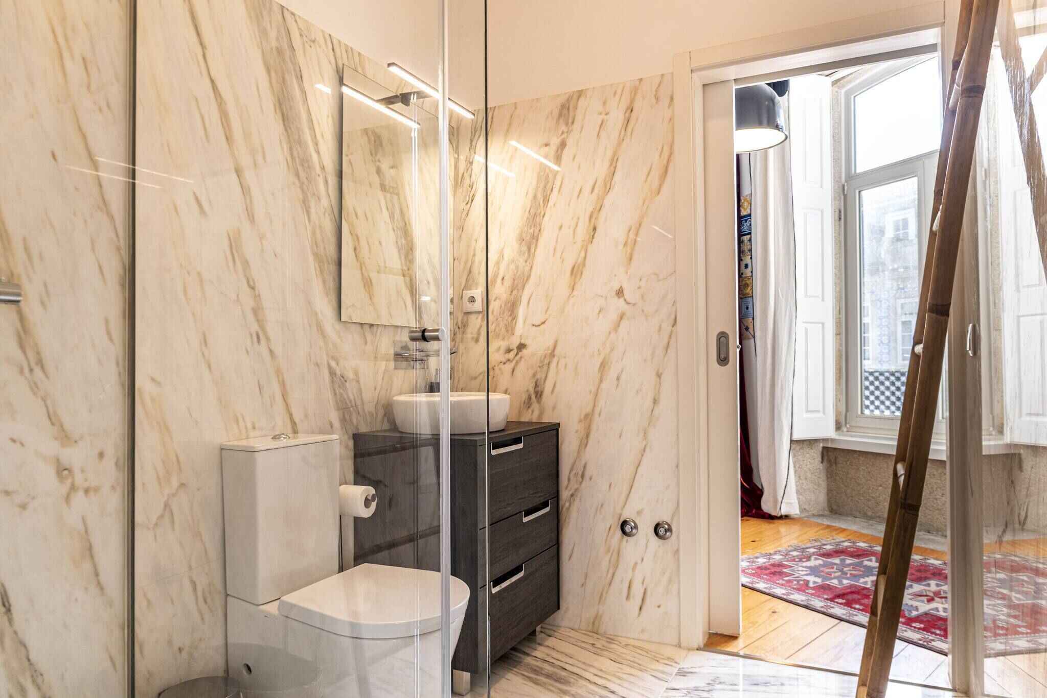 Ein modernes Badezimmer mit Glasdusche, Toilette, Waschtisch und Spiegel.