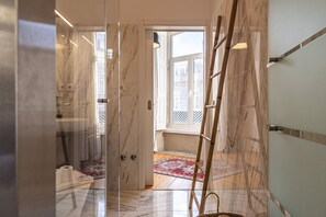 A hallway with marble walls, a wooden ladder, and a patterned rug.