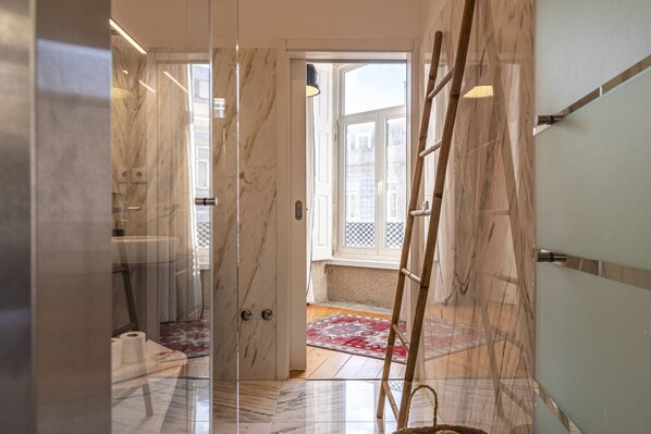 A hallway with marble walls, a wooden ladder, and a patterned rug.