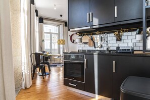 A modern kitchen with black cabinets, stainless steel appliances, and a dining area with a table and chairs.