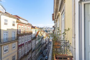 Eine schmale Straße gesäumt von mehrstöckigen Gebäuden mit Balkonen und freiem Blick auf die Stadt in der Ferne.
