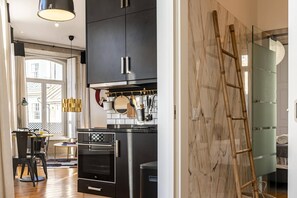 Una cocina moderna con armarios negros, electrodomésticos de acero inoxidable y una mesa de comedor de madera con sillas.