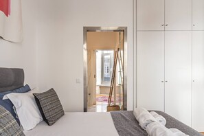 Ein Schlafzimmer mit Bett, Kleiderschrank und Blick auf einen Außenbereich.
