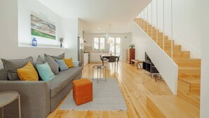 Un salon moderne avec un canapé gris, un escalier en bois et un coin repas.