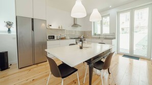 Une cuisine moderne dotée d’un grand îlot central, d’appareils électroménagers en acier inoxydable et de luminaires suspendus.