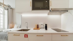 Una cocina moderna con armarios blancos, un microondas negro, una estufa empotrada y una campana extractora de acero inoxidable.