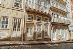 Un edificio con diverse finestre, un portone con un cartello e un muro decorato.