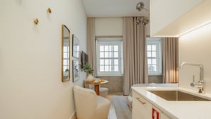 Ein modernes Badezimmer mit Waschbecken, Spiegel und einem kleinen runden Tisch mit Vase und Pflanze.