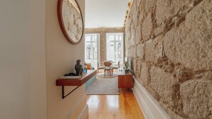 A modern interior with a stone wall, a round mirror, a dining area with chairs, and a small table. - Constituição Deluxe by Hosty (Oporto)