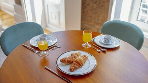 A round wooden table with two plates of croissants, a glass of orange juice, and a cup of tea. - Constituição Deluxe by Hosty (Oporto)