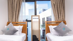 A hotel room with two beds, each with a pillow and a mirror. - Bloomfields Modern 2BR Azizi Gardens (Dubai)