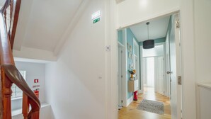 A staircase leading to a landing with a fire extinguisher and an emergency exit sign. - Bonfim Premium by Hosty (Porto)