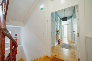 A staircase leading to a landing with a fire extinguisher and an emergency exit sign.