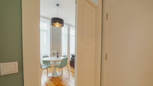 A room with a round table, four chairs, a hanging light fixture, and a door. - Bonfim Premium by Hosty (Porto)