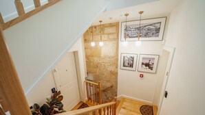 A staircase with wooden railings, a stone wall, and three framed pictures on the wall.