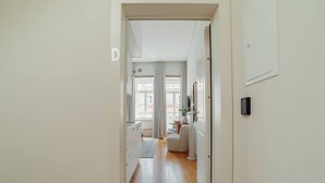 En hall som leder in till ett vardagsrum med en soffa, ett litet bord och en växt.