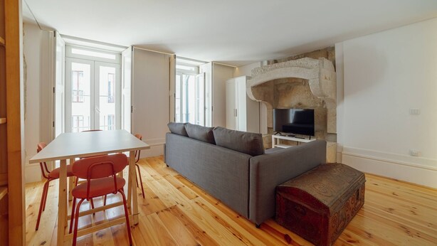 Un espacio habitable moderno con sofá, mesa de comedor y sillas, televisor y chimenea de piedra.