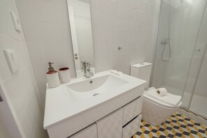 A bathroom with a white sink, mirror, toilet, and shower. - Cozy Almada by Hosty (Oporto)