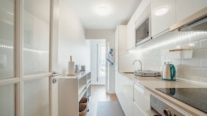 A modern kitchen with white cabinets, a microwave, an oven, and a sink. - Matosinhos Premium by Hosty (Senhora da Hora)