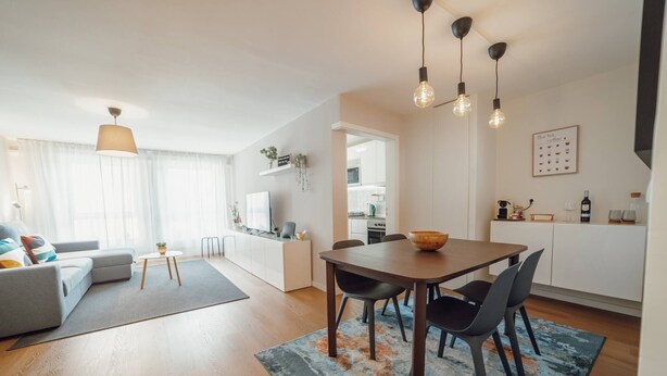 A modern living room with a sofa, a coffee table, and a dining area with a table and chairs. - Matosinhos Premium by Hosty (Senhora da Hora)