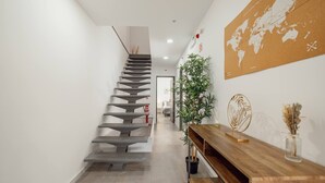 A modern staircase leading to a room, a wooden console table with decorative items, and a world map on the wall. - Amazing Villa by Hosty (Oporto)