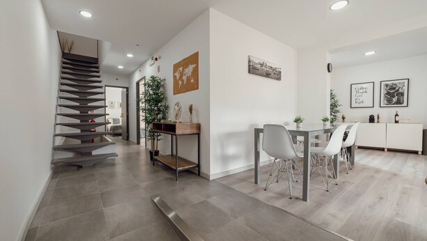 A modern interior with a staircase, a dining area with chairs and a table, and a kitchen area with cabinets and a refrigerator. - Amazing Villa by Hosty (Oporto)