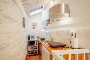 A compact kitchen with a microwave, toaster, and sink. There is a small shelf with kitchen utensils and a dish rack above the sink. - Charming Tiny House by Hosty (Porto)
