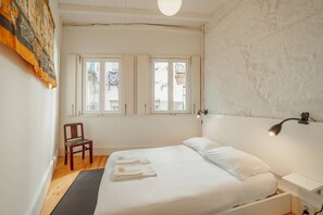 A bedroom with a bed, a chair, a nightstand, and a lamp.