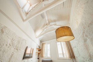 A room with a high ceiling, exposed beams, and a large window with curtains. - Charming Tiny House by Hosty (Porto)