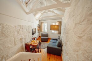 A cozy room with a high ceiling, a dining area with a table and chairs, a sofa, and a lamp. - Charming Tiny House by Hosty (Porto)